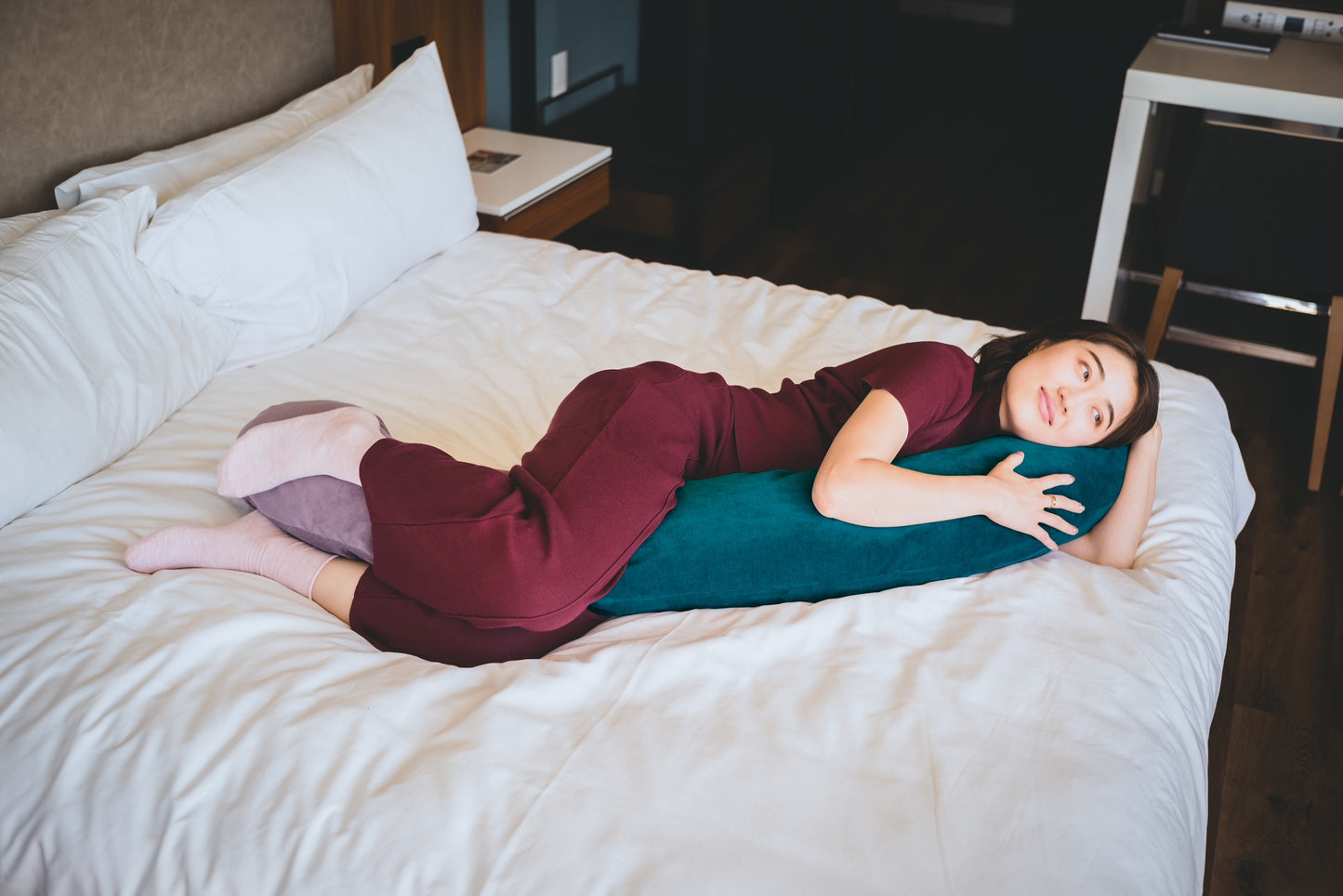 Woman lying on bed looking relaxed with her hiamom body pillow