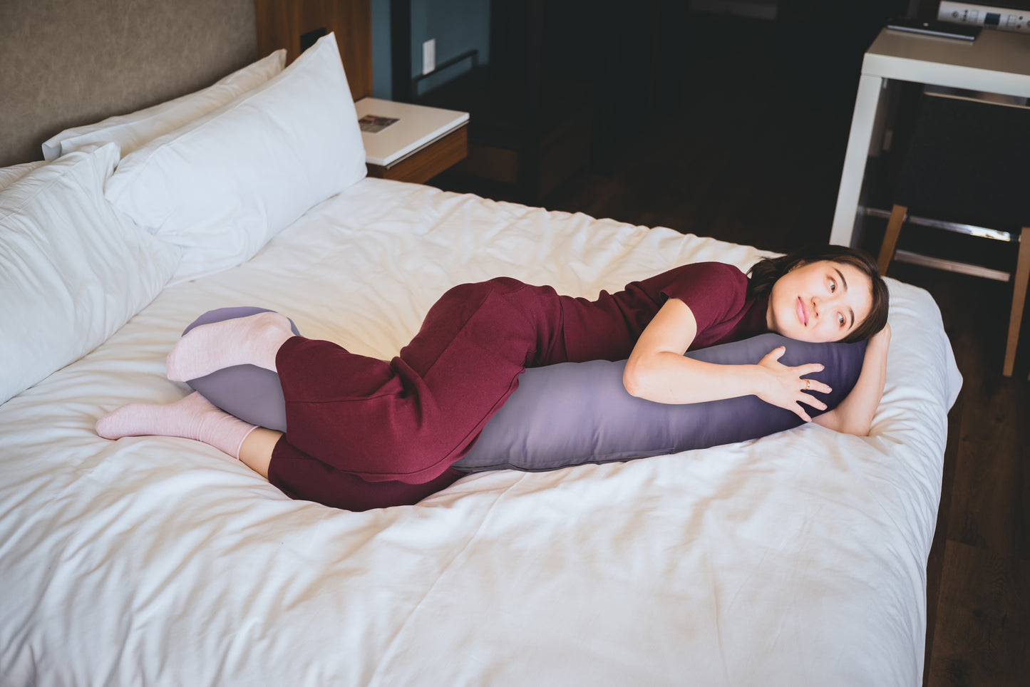 Woman lying on bed with hiamom body pillow as a support